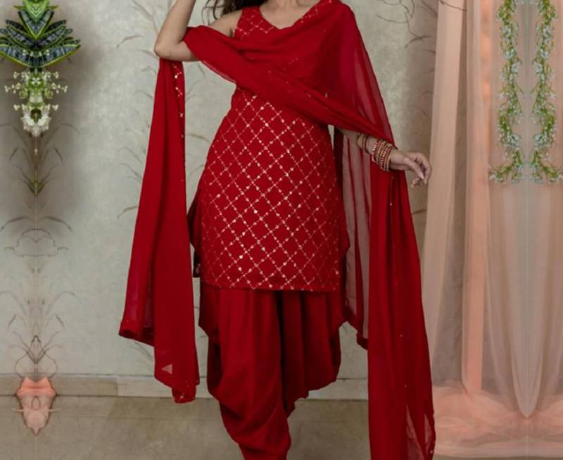 Luxurious red silk suit from D G Collection displayed elegantly in Devghar, showcasing its rich texture and vibrant color.