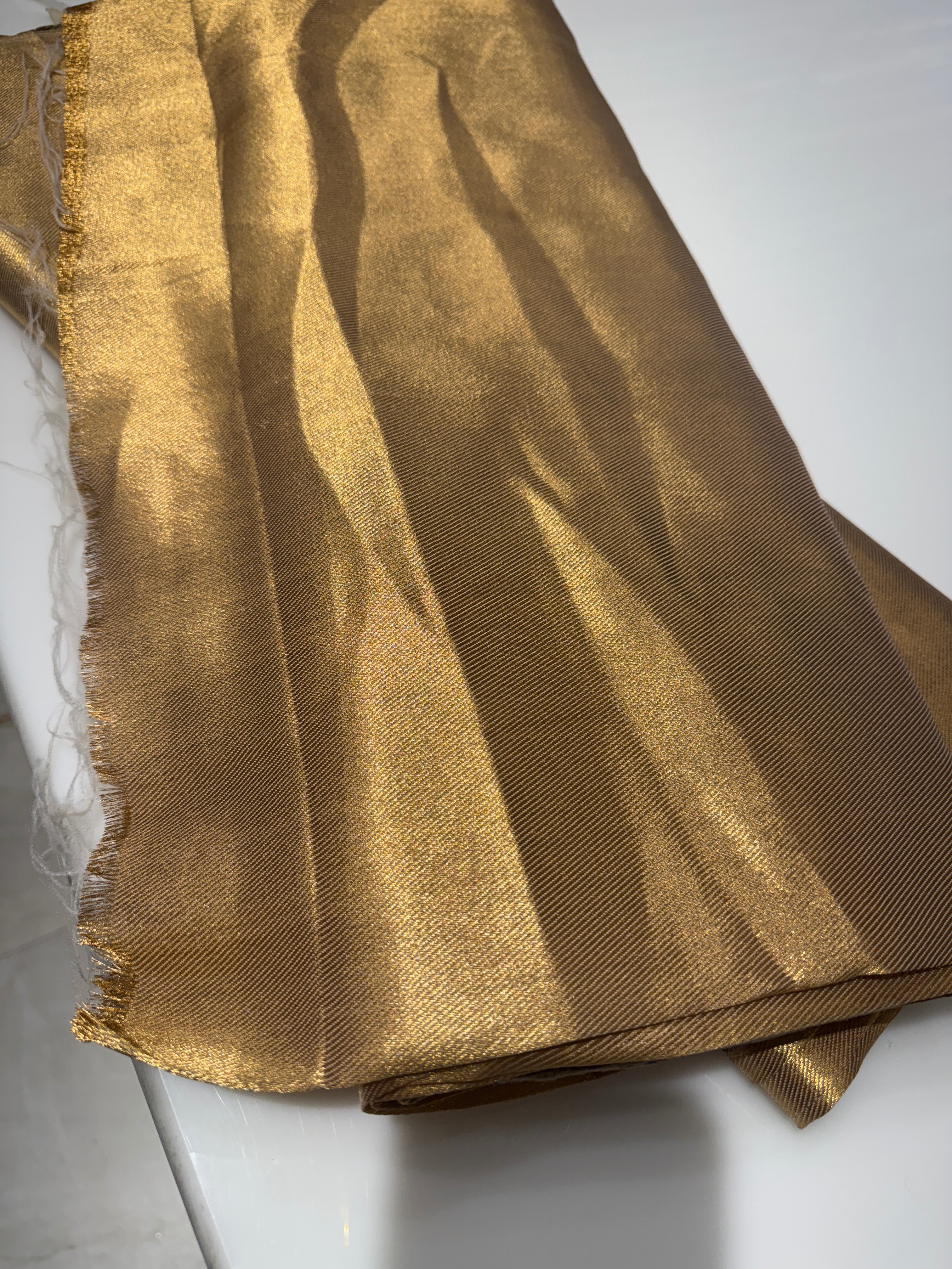 Luxurious golden satin fabric draped elegantly, showcasing its smooth texture and shine, perfect for drapery in Patiala.