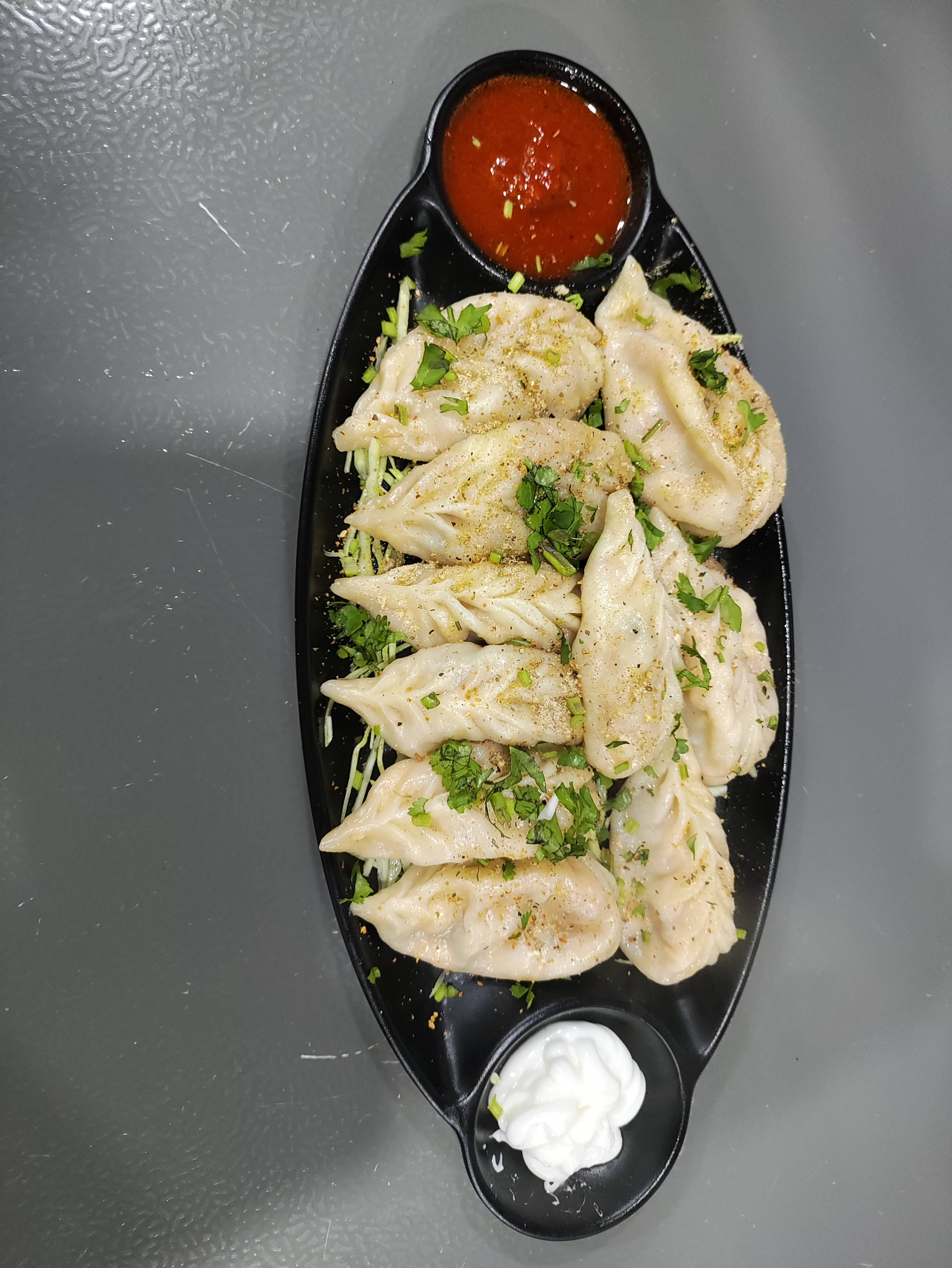 Delicious Tibetan Steamed Momos served in a bamboo basket with a side of dipping sauce in Bikaner.