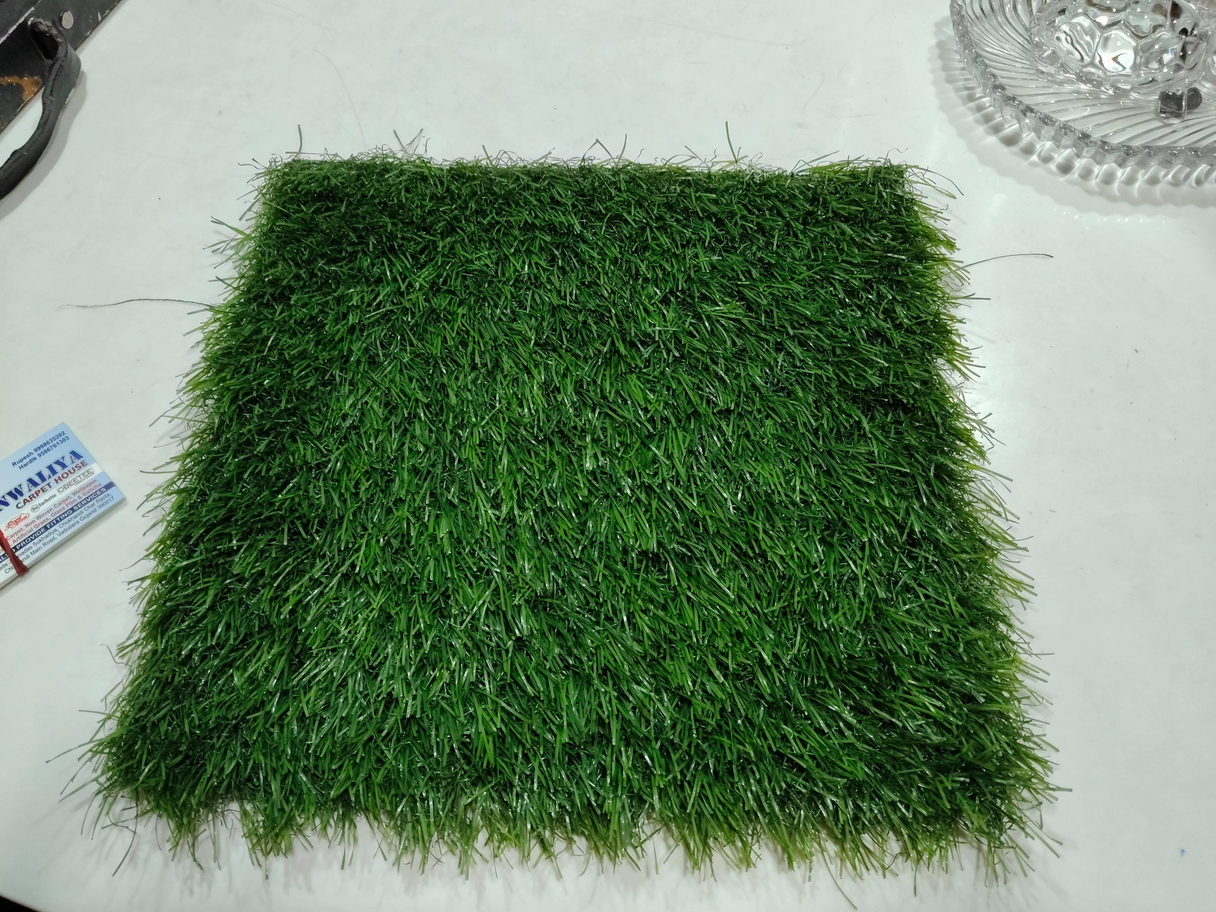 Lush green artificial grass installed in a garden setting in Vadodara, showcasing its vibrant color and realistic texture, pe