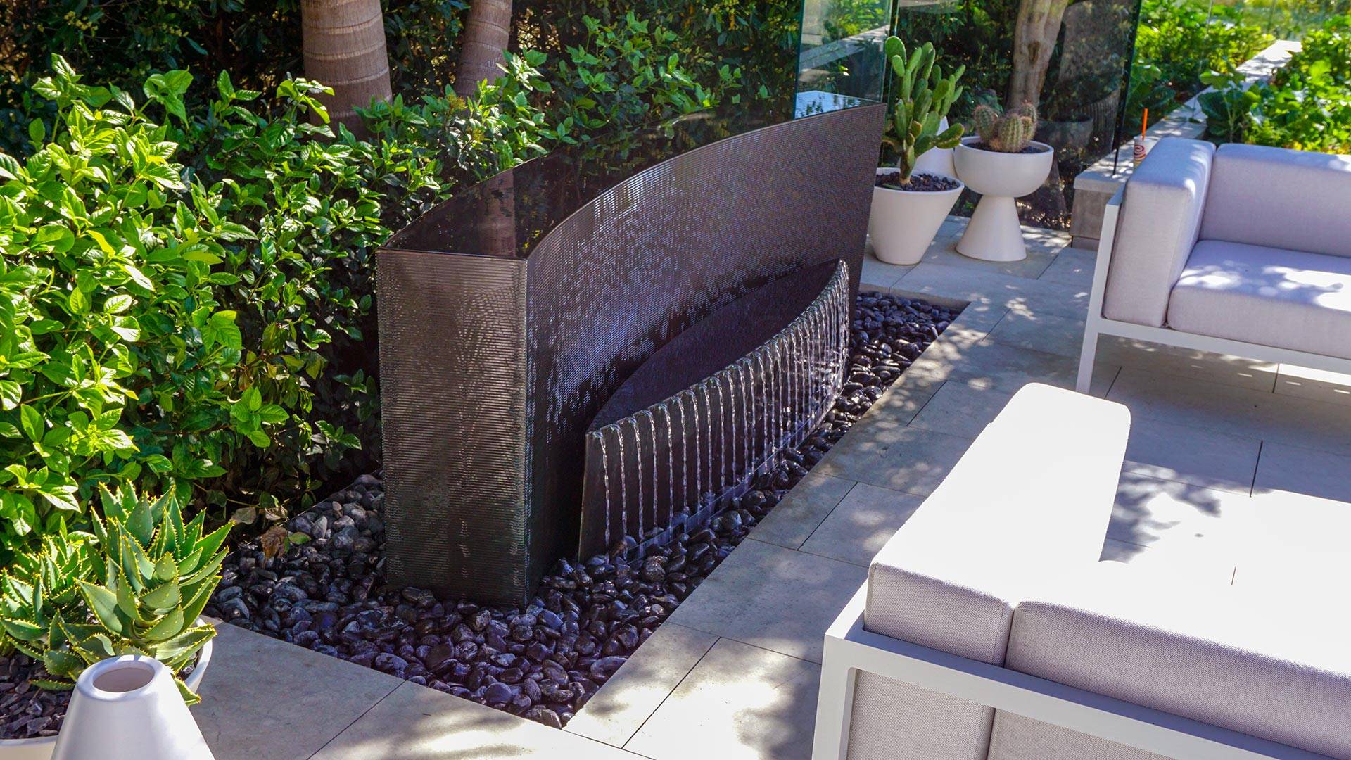 Elegant cascading copper Rivulet Water Feature in Delhi with textured water flow and river rocks, enhancing outdoor aesthetic