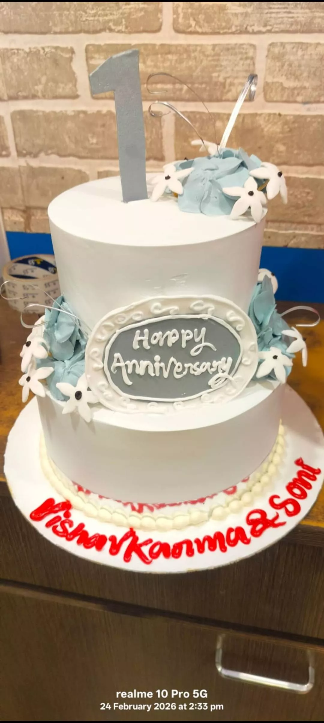 Two-tier Monginis Marachiya 1st Anniversary Cake decorated with beautiful fondant flowers, available in Mirganj.