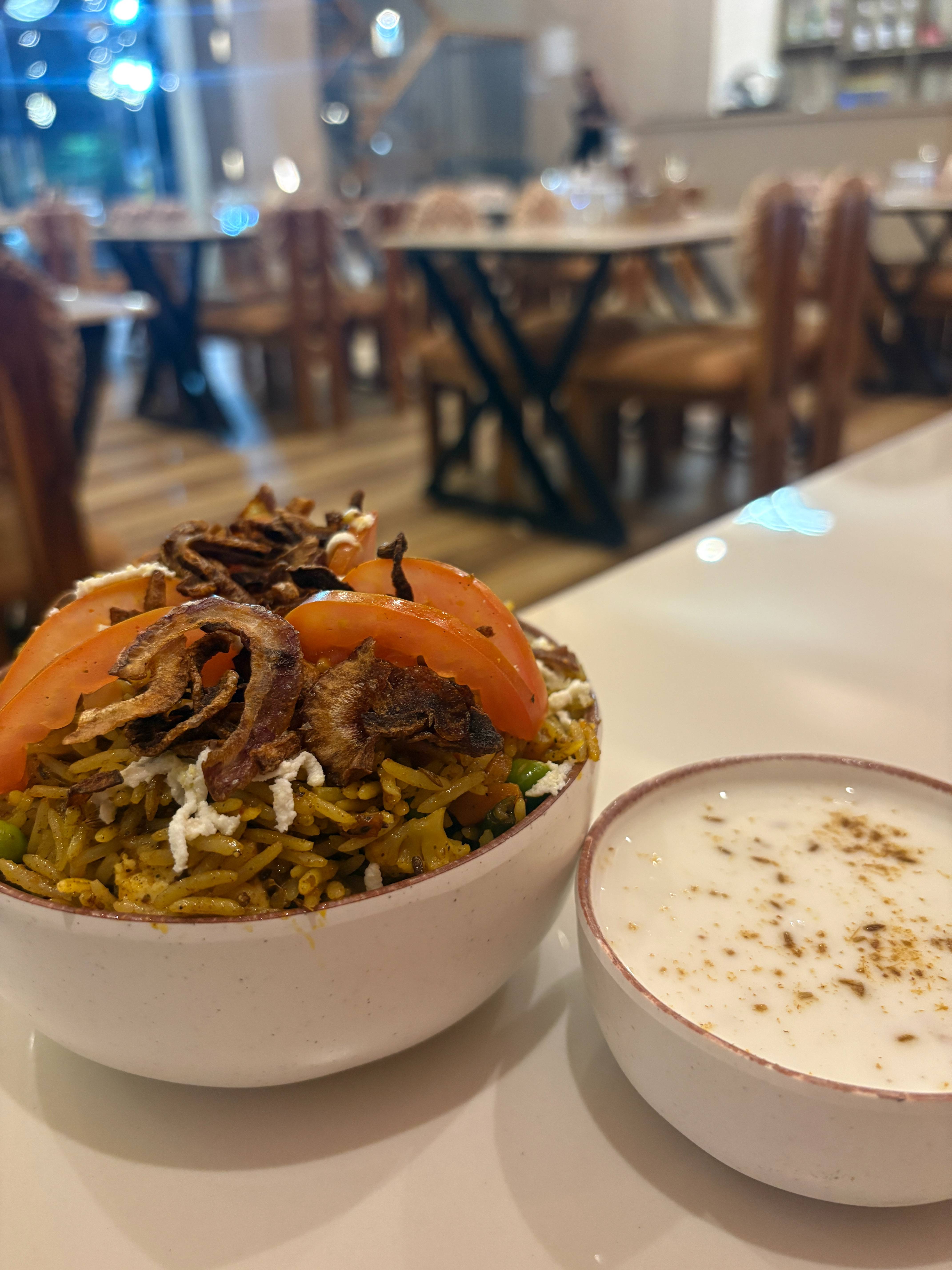 Aromatic Vegetable Biryani served with fresh raita, featuring basmati rice and vibrant vegetables at THE FORTRESS CAFE AND MU