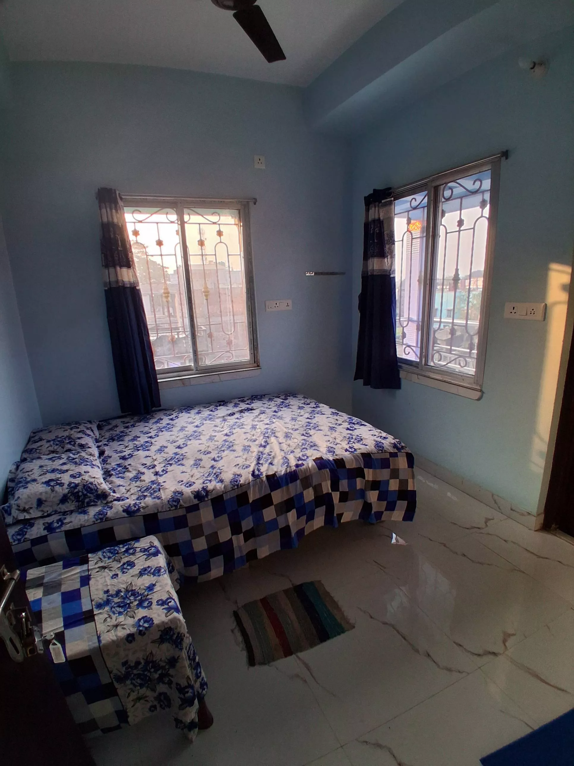 Elegant double bed room with blue floral bedsheet set in NABADWIP, designed for 2 adults and 1 child, featuring an attached b
