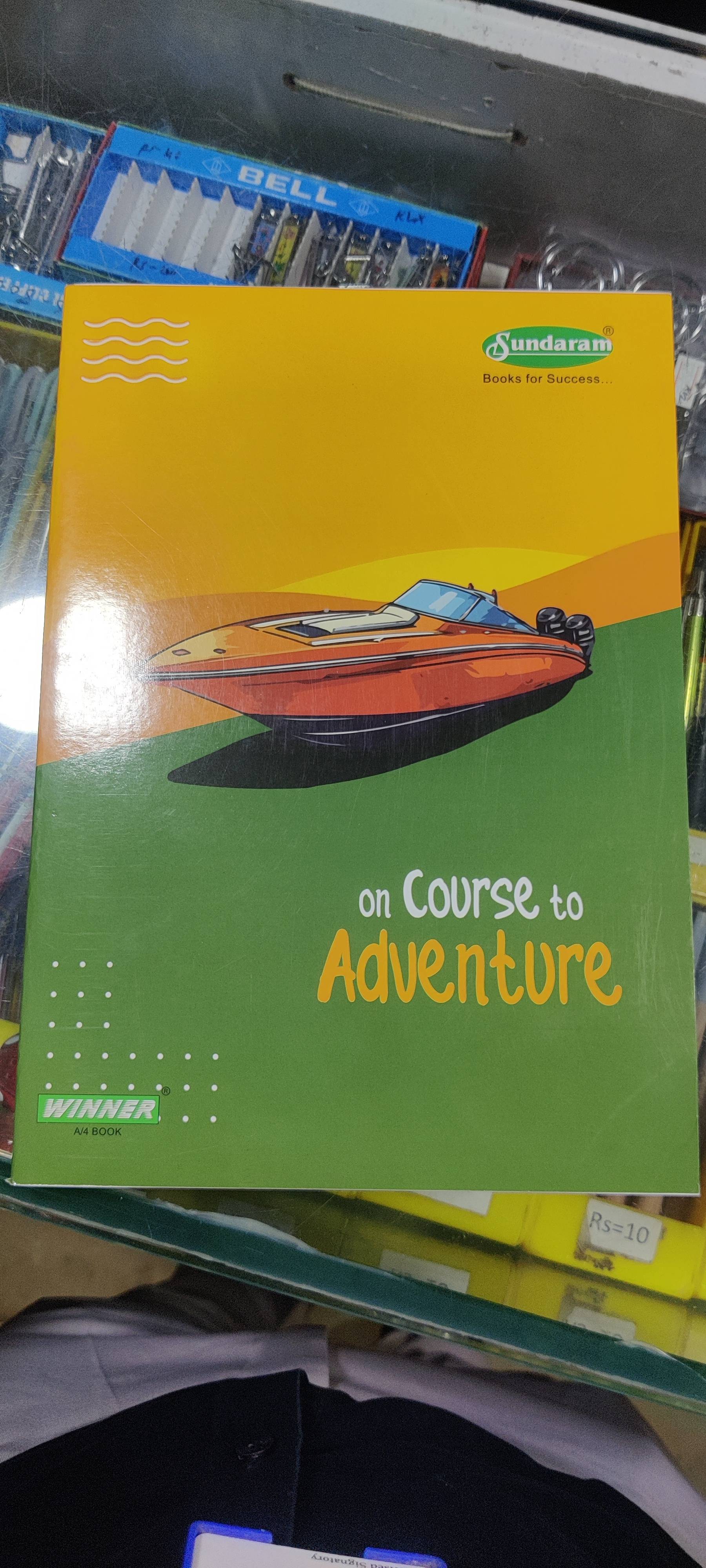 Sundaram Winner A4 Book featuring an adventure theme, displayed on a desk with colorful writing tools in KOTHRUD