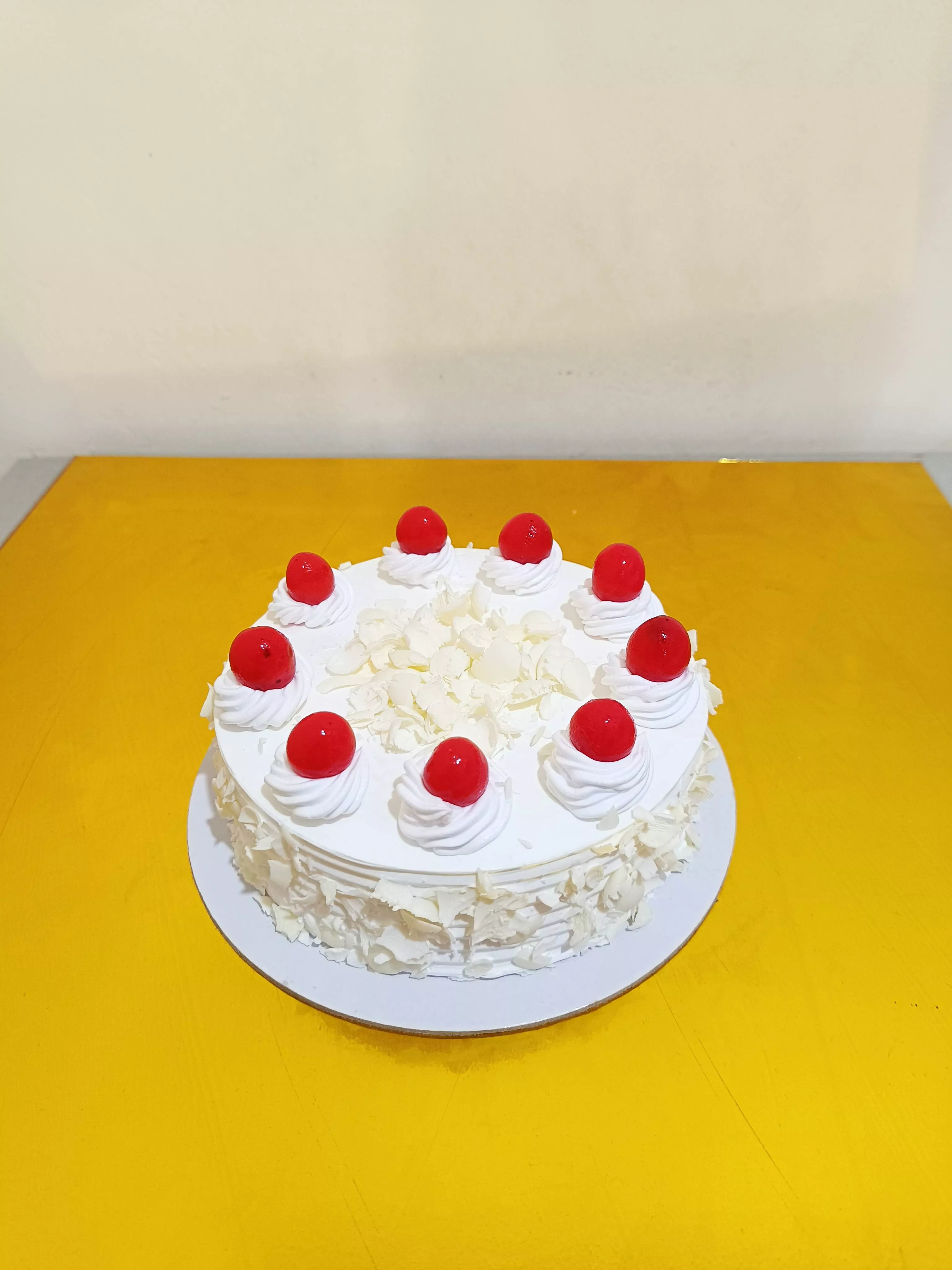 Delicious White Forest Cake topped with cherries and white chocolate from VARNIKA PATISSERIE in Bangalore, showcasing creamy 