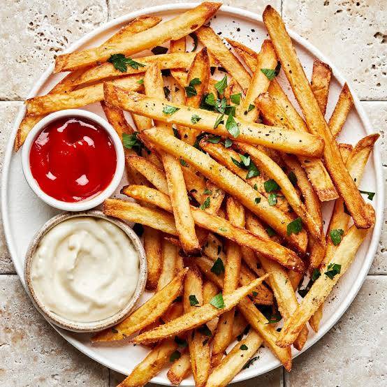 Golden crispy French fries served with dipping sauces in Kolkata